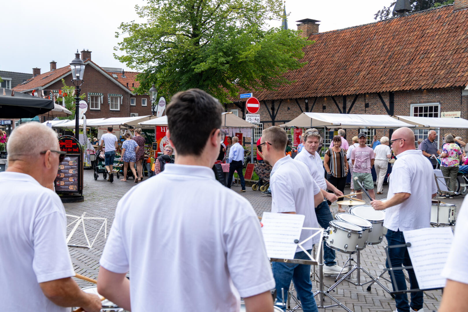Boerenmarkt Losser 29 augustus 2026 Muziekkapel speelt op een levendig marktplein met marktkramen en talrijke bezoekers.